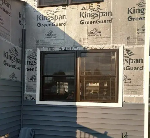 KPI Jr Exteriors crew inspecting exposed sheathing and installing a water-resistive barrier during a siding replacement